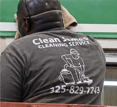 James wiping down a surface while wearing a Clean James Cleaning Services shirt