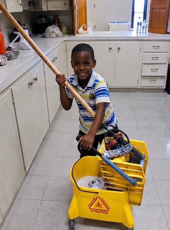 A boy with a mop and a yellow caution bucket
